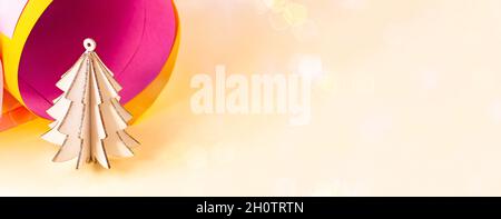 Albero di Natale in legno bianco brillante su carta colorata rosa e gialla rotola sfondo astratto con spazio copia. Semplice divieto di Capodanno e festività natalizie Foto Stock