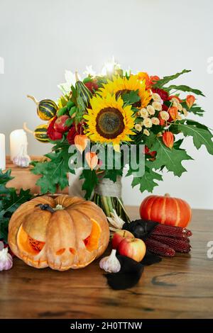 Concetto di tema di Halloween: Zucche, candele, girasole, ragni e altri attributi al tavolo. Zucca d'arancia di Halloween con il male Jack o'lantern paura faccia. Foto verticale di alta qualità Foto Stock