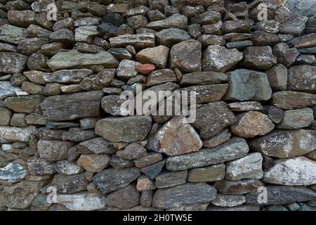 Muro di pietra fatto con rocce senza calcestruzzo. Una struttura unica può essere utilizzata come sfondo. Foto Stock