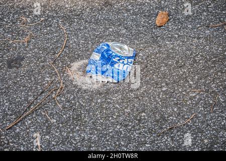 Una birra blu buca leggera può essere scaricata nel parcheggio del parco schiacciato sulla spazzatura asfalto inquinando l'ambiente Foto Stock
