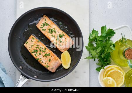 Sopra di filetto di salmone succoso fritto con prezzemolo e limone su padella Foto Stock