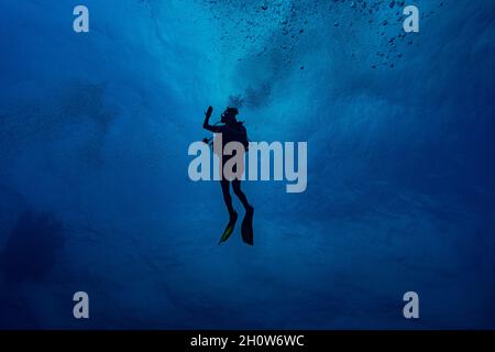 Donna subacquea nuoto in blu profondo Foto Stock