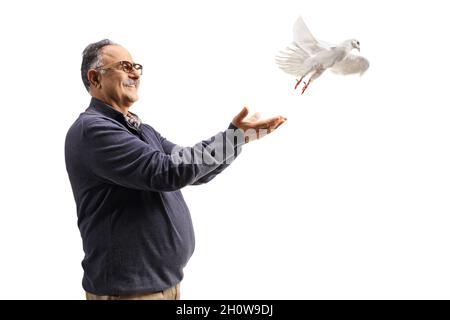 Uomo maturo sorridendo e lasciando una colomba bianca volare isolato su sfondo bianco Foto Stock