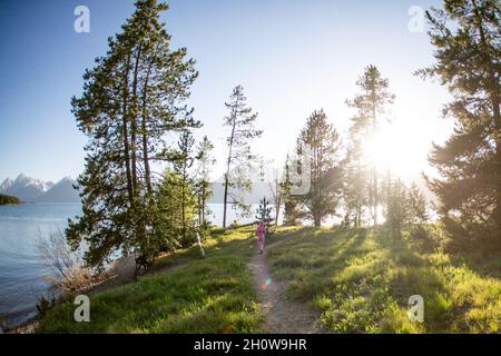 Giovane ragazza che corre lungo un sentiero in una giornata di sole a Grand Teton Foto Stock