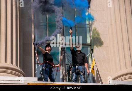 Washington, Stati Uniti. 14 Ott 2021. Gli attivisti ambientali del gruppo Extinction Rebellion fanno ondare bombe fumogene fuori da una seconda finestra della Camera di Commercio degli Stati Uniti come una protesta della posizione dell'organizzazione sul cambiamento climatico a Washington, DC il 14 ottobre 2021. Gli attivisti hanno raggiunto la seconda parte della scala per svelare due grandi striscioni, e sono stati interrogati e rilasciati dalla polizia alla loro discesa. (Foto di Matthew Rodier/Sipa USA) Credit: Sipa USA/Alamy Live News Foto Stock