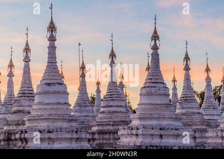 Stupa bianchi intorno a Sandamuni Sandamani o Sandar Mu Ni pagoda durante il tramonto a Mandalay, Myanmar Foto Stock