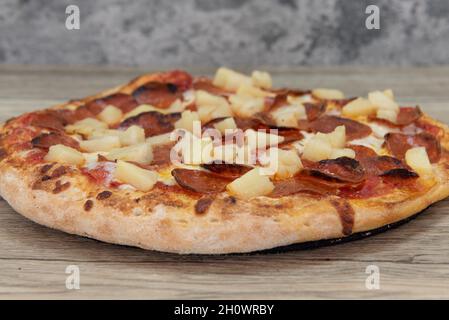 Pizza al cavolfiore appena sfornata con condimenti di verdure tritati servita su un piatto di legno. Foto Stock