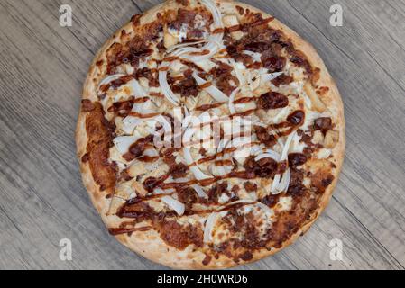 Vista dall'alto della pizza di pollo al barbecue appena sfornata con condimenti di carne tritati serviti su un piatto di legno. Foto Stock
