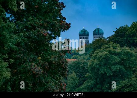 Le famose torri gemelle della Frauenkirche di Monaco di Baviera sovrastano alberi dai colori autunnali dal punto di vista del Giardino Englisch di Monaco. Foto Stock