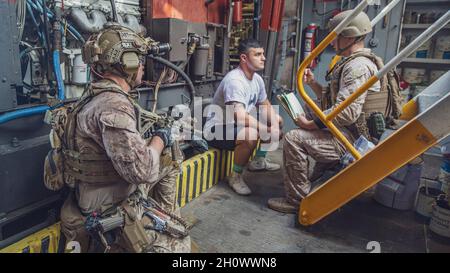 ATTIVITÀ DI SUPPORTO NAVALE BAHRAIN (SETTEMBRE 22, 2021) – Marines assegnato alla 11a unità Marine Expeditionary (MEU), domanda un giocatore di ruolo detenuto a bordo della flotta Ocean Tug USNS Catawba (T-ATF 168) durante una visita, bordo, ricerca, e sequestro esercizio, settembre 22. L'undicesimo MEU è schierato nell'area della 5th Fleet degli Stati Uniti di operazioni a sostegno delle operazioni navali per garantire la stabilità e la sicurezza marittima nella regione centrale, collegando il Mediterraneo e il Pacifico attraverso l'Oceano Indiano occidentale e tre punti di arresto strategici. (STATI UNITI Corpo marino Foto di staff Sgt. Victor Mancilla) Foto Stock