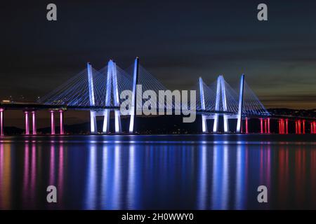 Il Governatore Mario M. Cuomo Bridge, illuminato in rosso, bianco e blu in riconoscimento del Columbus Day, attraversa il fiume Hudson subito dopo il tramonto. Foto Stock