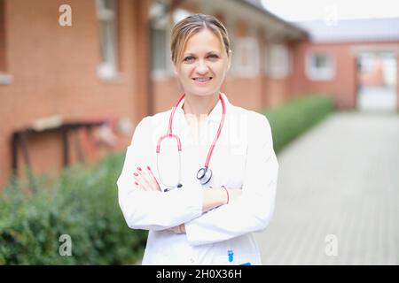 Ritratto di una donna sorridente medico con le braccia ripiegate sulla strada Foto Stock