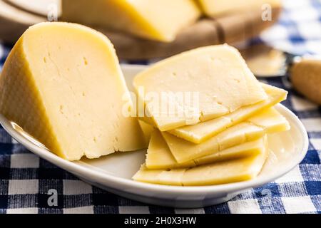 Blocco di formaggio duro. Formaggio affettato sul piatto. Foto Stock
