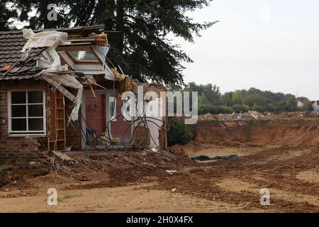 Erftstadt, Germania. 13 ottobre 2021. Una casa distrutta si erge sul bordo della demolizione fino alla fossa di ghiaia nel quartiere di Blessem. Lì, nella notte del 15 luglio, la terra si aprì e inghiottì diverse case. Il foro è un'attrazione, la foto aerea di esso è andato intorno al mondo. (A dpa: ''questo è ciò che si prende alla tomba' - Un quarto d'anno dopo l'alluvione') credito: Oliver Berg/dpa/Alamy Live News Foto Stock