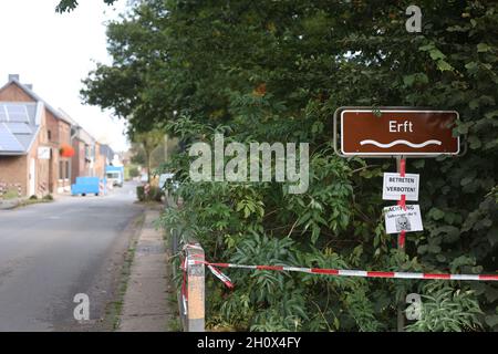 Erftstadt, Germania. 13 ottobre 2021. Un cartello dietro un nastro di barriera su un ponte punta al fiume Erft nel distretto di Blessem, sotto il quale si trovano ulteriori indicazioni che dicono "non entrare" e "attenzione, pericolo per la vita". A Blessem, la terra si aprì nella notte del 15 luglio e inghiottì diverse case. (A dpa: ''You take that to the grave' - Un quarto d'anno dopo l'alluvione') Credit: Oliver Berg/dpa/Alamy Live News Foto Stock