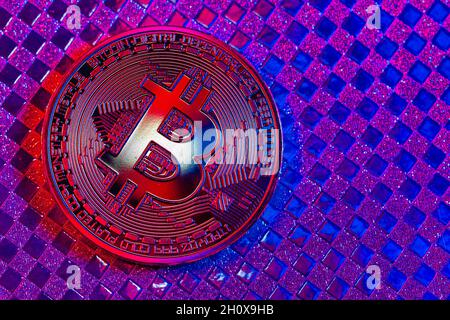 Bitcoin d'oro in una luce mista blu e rossa su uno sfondo colorato Foto Stock