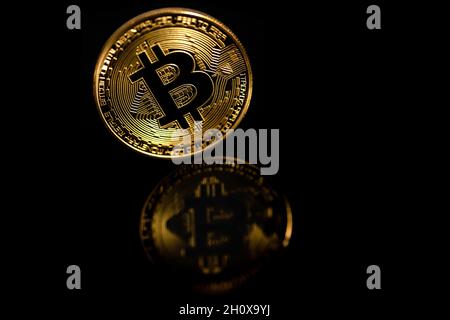 Primo piano bitcoin dorato con riflesso isolato su sfondo nero. Bitcoin si riflette nello specchio. Foto Stock