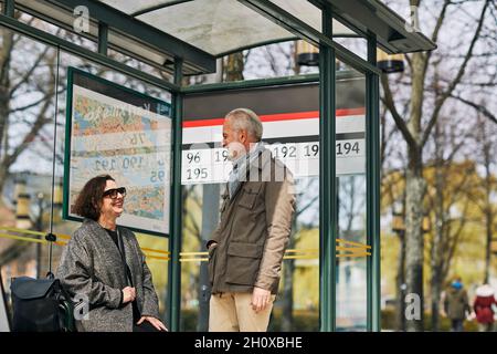 Coppia matura che parla alla fermata dell'autobus Foto Stock
