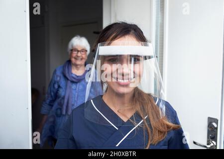 Infermiere femmina che indossa la visiera protettiva Foto Stock