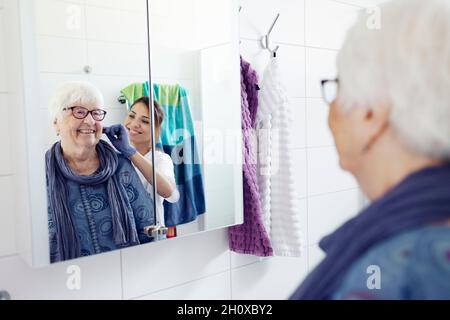 Nurse pettinare i capelli della donna in bagno Foto Stock
