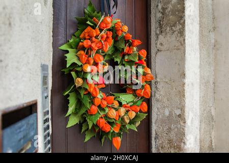 Corona autunnale con Physalis su una porta di legno Foto Stock