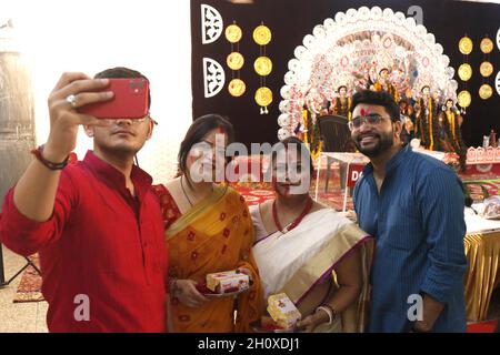 New Delhi, India. 15 ottobre 2021. Le donne strisciare sindoor o vermilion sui volti degli altri durante Khela indoor l'ultimo giorno del festival Durga Puja ad Aaram Bagh Pooja Samiti a Nuova Delhi, il venerdì 15 ottobre 2021. Sindur khela e l'immersione o visarjan della dea Durga hanno avuto luogo senza il fervore usuale dovuto Covid-19 Pandemic. La tradizionale khela di sindur dove le donne sposate hanno messo vermilion l'una sull'altra era per lo più limitata a pochi residenti locali ed organizzatori ai pandals. Foto di Akash Anshuman/ABACAPRESS.COM Credit: Abaca Press/Alamy Live News Foto Stock