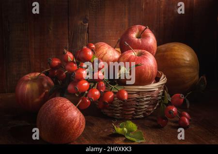 mele e altri frutti su sfondo di legno scuro in stile rustico Foto Stock