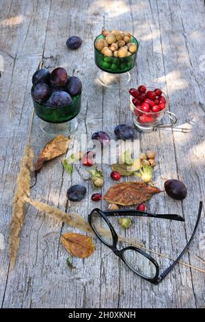 Colpo verticale di foglie autunnali, frutta e noci su superficie di legno come sfondo di caduta bello Foto Stock