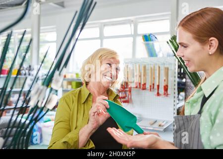 Sorridendo il cliente che riceve consigli da un venditore in un giardino o in un negozio di hardware Foto Stock
