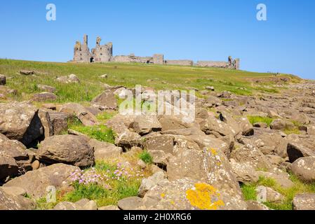 Dunstanburgh Castle Northumberland Inghilterra visto dalla costa rocciosa vicino al villaggio di Crafer Northumberland Coast Inghilterra GB UK Europe Foto Stock