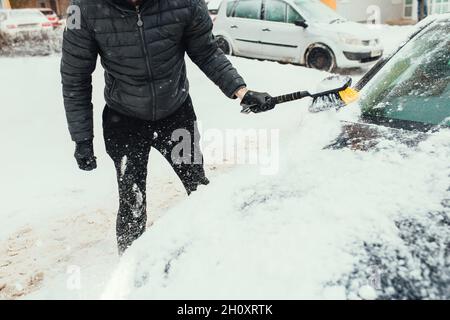 Sgombrare la neve dal vetro e dal corpo dell'automobile dopo la nevicata pesante in inverno Foto Stock