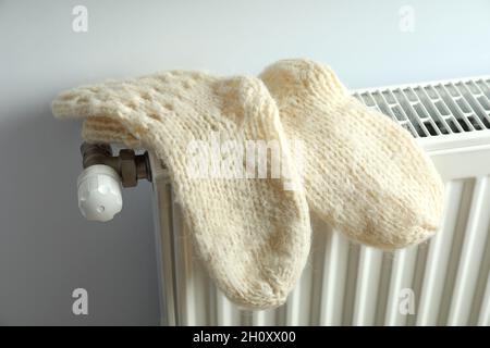 Concetto di stagione di riscaldamento con calze in maglia su radiatore. Foto Stock