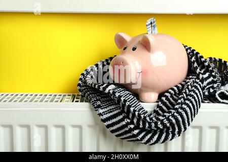 Concetto di stagione di riscaldamento con banco di maialino su radiatore. Foto Stock