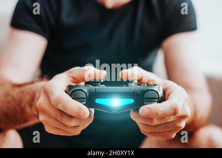 Uomo che gioca con una console di gioco - gamepad in mani - bambino adulto Foto Stock