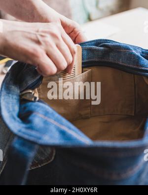 Una donna ordinata e ordinata mette un hairbrush di legno nella tasca del suo sacchetto - mantenga un aspetto pulito Foto Stock