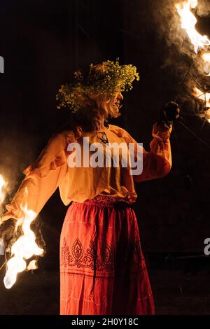 ARD, ROMANIA - 21 agosto 2021: Una giovane donna rumena che gioca con il fuoco al buio durante una festa medievale ad Ardud Foto Stock