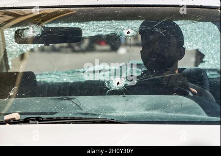 Beirut, Libano. 15 ottobre 2021. Un uomo si siede all'interno della sua auto trainata da proiettili nel Tayouneh, dopo i violenti scontri di ieri tra militanti sciiti musulmani di Hezbollah pro-iraniano e avversari. Almeno sei persone sono state uccise e 32 altre sono state ferite a Beirut oggi in colpi di arma da fuoco e scontri per una protesta contro un giudice che indaga l'esplosione massiccia dell'anno scorso al porto della città. Credit: Marwan Naamani/dpa/Alamy Live News Foto Stock