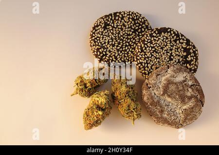 La marijuana fiorisce e dolci isolati su sfondo bianco. Fiori di cannabis e biscotti da vicino. Illuminato dalla luce del sole. Canapa ricreazione, canna kitch Foto Stock