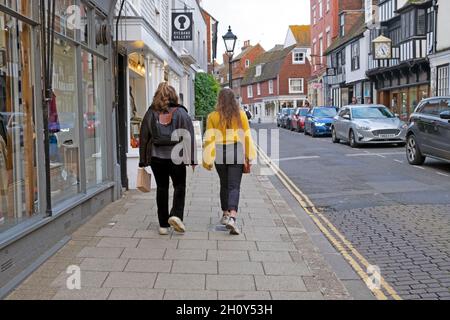 Vista posteriore di due giovani donne che camminano lungo High Street nella città di Rye East Sussex Inghilterra Gran Bretagna Regno Unito KATHY DEWITT Foto Stock