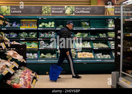 Uno shopper attraversa la navata delle insalate in un ramo di Tesco nel sud di Londra. Gli acquirenti sono detti per comprare una zattera di articoli di Natale, come regali e tacchini congelati, presto in un'offerta per assicurarsi che le loro feste non sono pesantemente disturbati per un secondo anno. Data foto: Venerdì 15 ottobre 2021. Foto Stock