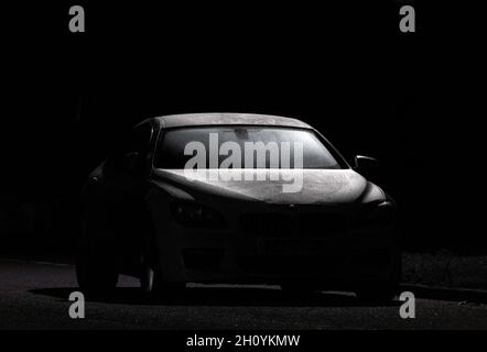 Vettura sportiva in pre-luce sotto la luce di un lampione di colore scuro Foto Stock
