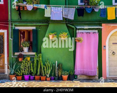 Vestiti appesi contro la colorata casa dipinta sul fronte dell'isola di burano Foto Stock