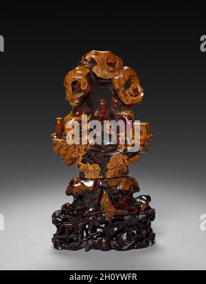 Bodhisattva Guanyin seduto in una roccia Grove, 1675-1700. Cina, dinastia Qing (1644-1911). Ocra opaco e traslucido rosso-arancione ambra; complessivo: 22,9 cm (9 in.). Foto Stock