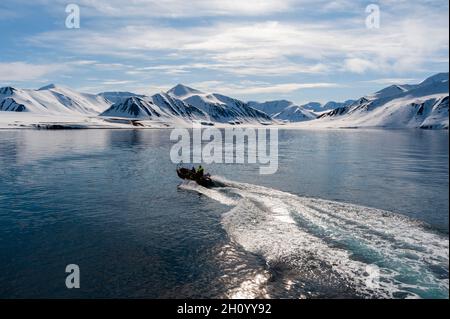 Un gommone naviga verso la riva sulla baia di Mushamna. Spitsbergen Island, Svalbard, Norvegia. Foto Stock