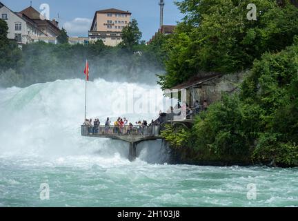 Schaffhausen, Germania - 9 agosto 2021: Piattaforma turistica direttamente sulle acque selvatiche delle Cascate del Reno Foto Stock