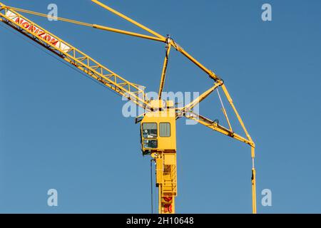 Una gru a torre gialla al lavoro a Glasgow contro un cielo blu chiaro sfondo Foto Stock