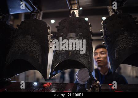 (211015) -- WUHAN, 15 ottobre 2021 (Xinhua) -- un membro dello staff regola le campane del suono dopo che sono state trasferite ad una sala di esposizione di nuova costruzione del Museo Provinciale di Hubei a Wuhan, provincia centrale di Hubei in Cina, 15 ottobre 2021. Il set di campane di carillon è stato recentemente rilocato al nuovo progetto della terza fase del museo. Credit: Xinhua/Alamy Live News Foto Stock