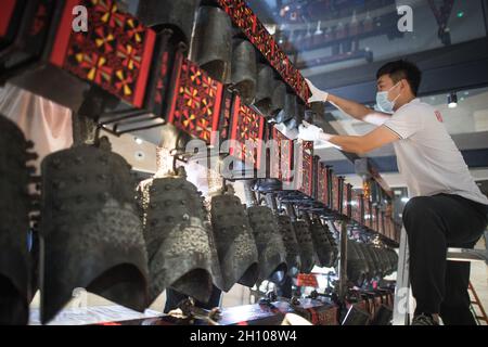 (211015) -- WUHAN, 15 ottobre 2021 (Xinhua) -- un membro dello staff regola le campane del suono dopo che sono state trasferite ad una sala di esposizione di nuova costruzione del Museo Provinciale di Hubei a Wuhan, provincia centrale di Hubei in Cina, 15 ottobre 2021. Il set di campane di carillon è stato recentemente rilocato al nuovo progetto della terza fase del museo. Credit: Xinhua/Alamy Live News Foto Stock