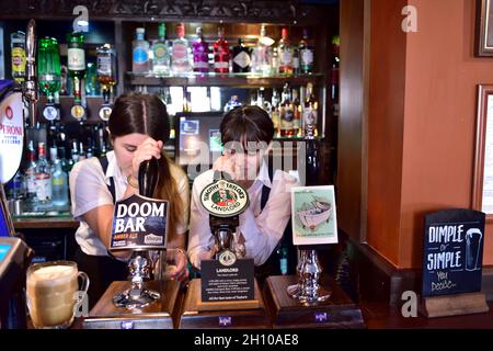 Due attraenti baristi femminili che tirano le pinte dietro le pompe di birra a mano nel pub Tap & Spile Birmingham, Regno Unito Foto Stock