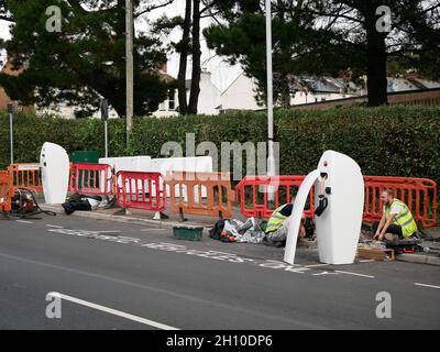 Appaltatori che installano punti di ricarica per veicoli elettrici a bordo del marciapiede su una strada a Exeter, Devon UK Foto Stock